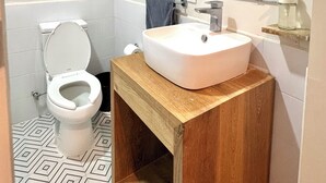 A bathroom with a white toilet, a wooden vanity with a sink, a towel rack, and a mirror.