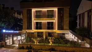 A modern hotel with a prominent entrance, a well-lit facade, and a visible sign for Solmare Suites. - KONYAALTI PLAJINA YAKIN,ŞIK VE YENİ 1+1 SUİT DAİRELER (Antalya)