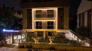 Ein modernes Hotel mit markantem Eingangsbereich, einer gut beleuchteten Fassade und einem sichtbaren Schild für Solmare Suites.