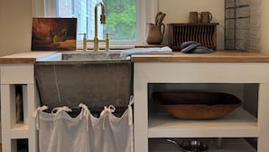 A kitchen with a window, a sink, a wooden bowl, and a shelf with kitchenware. - Charming Retreat steps from the Erie Canal (Albion)