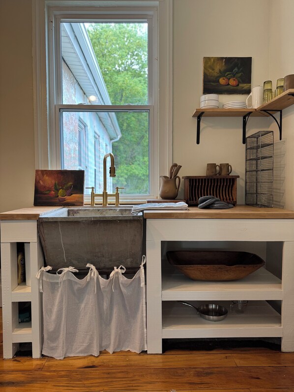 A kitchen with a window, a sink, a wooden bowl, and a shelf with kitchenware. - Charming Retreat steps from the Erie Canal (Albion)