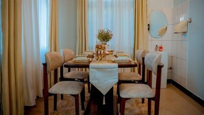 Een eethoek met een tafel voor zes personen, omringd door stoelen, en een bloevas op de tafel.