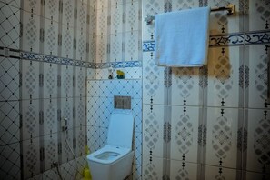 Une salle de bain avec des toilettes, un porte-serviettes et des carreaux décorés.