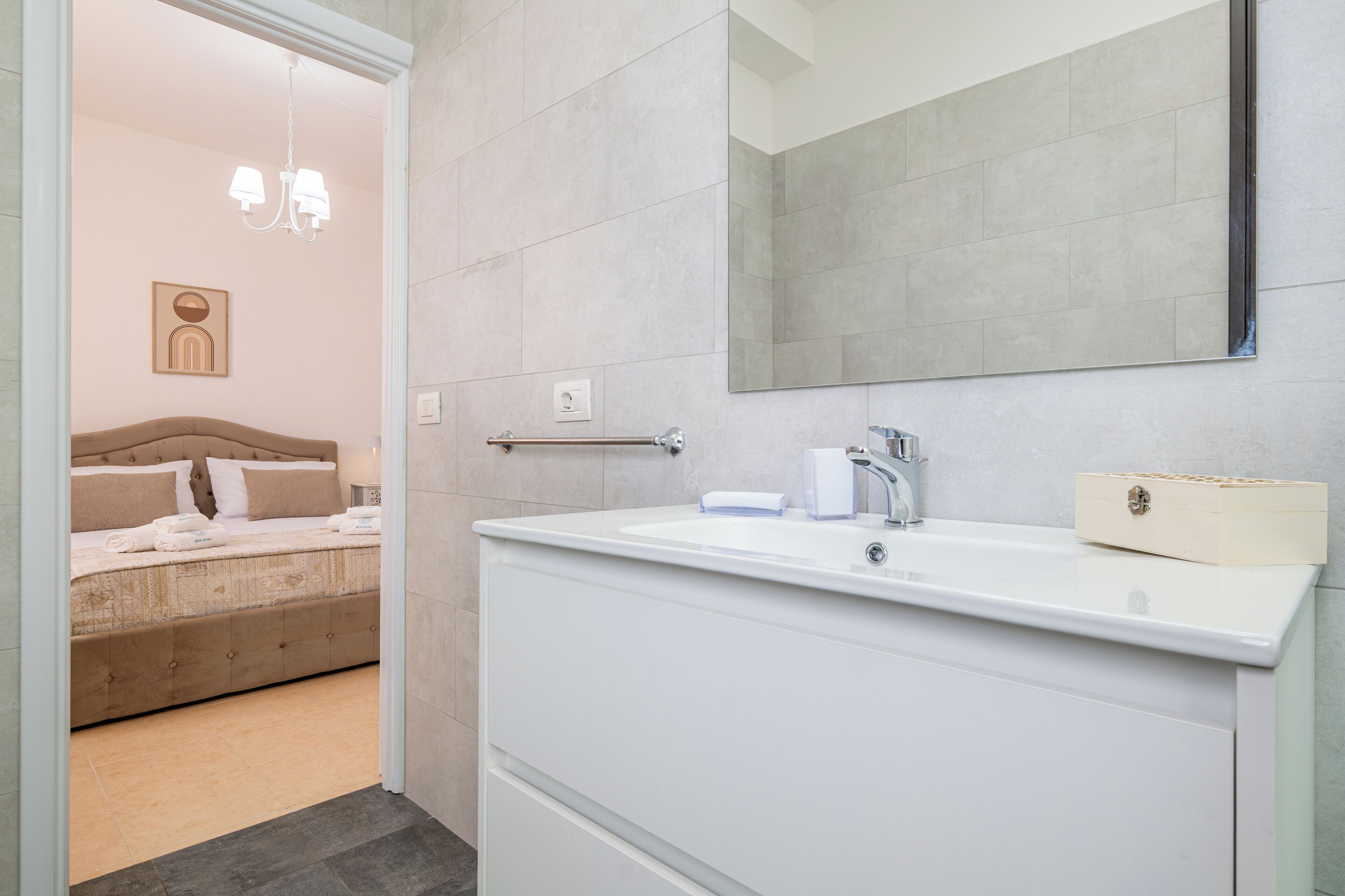 Un baño moderno con un espejo grande, un lavabo blanco y un perchero para toallas.