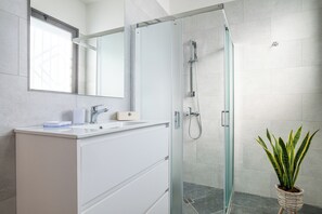 A modern bathroom with a glass-enclosed shower, a white vanity with a mirror, and a potted plant. - Deva Room (Ugento)