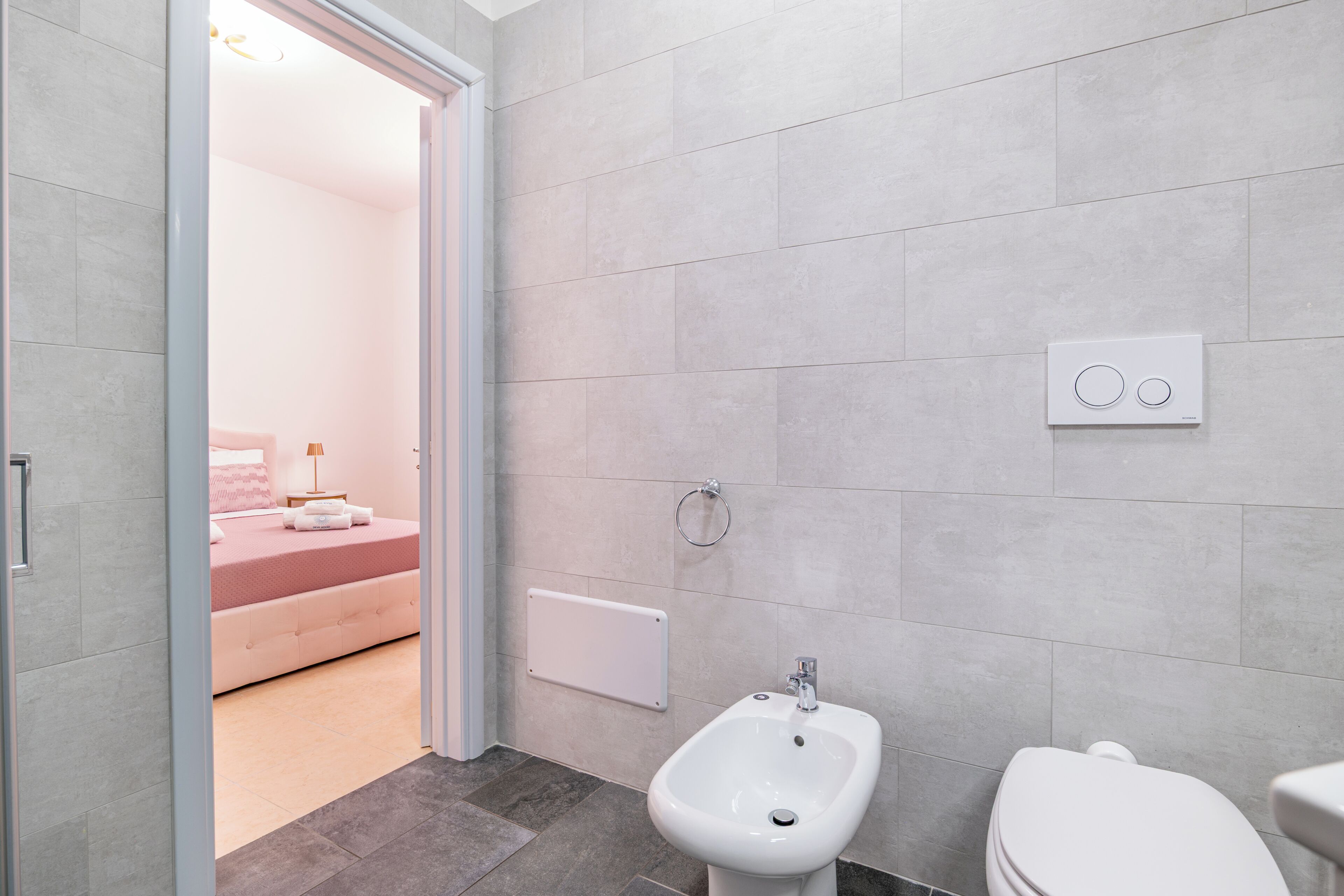 A bathroom with a bidet, toilet, and a control panel on the wall.