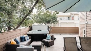 Eine Terrasse im Freien mit Whirlpool, Sitzgelegenheit und Tisch.