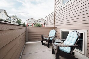 Un espace patio avec deux chaises en bois et une petite table, entouré d’une clôture en bois.