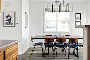 Un comedor moderno con una mesa rectangular, seis sillas y una lámpara colgante.