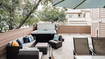An outdoor patio area with a hot tub, seating, and a table.