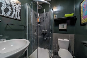 A bathroom with a glass-enclosed shower, a white sink, and a toilet. - Charming studio flat near Notting Hill (London)