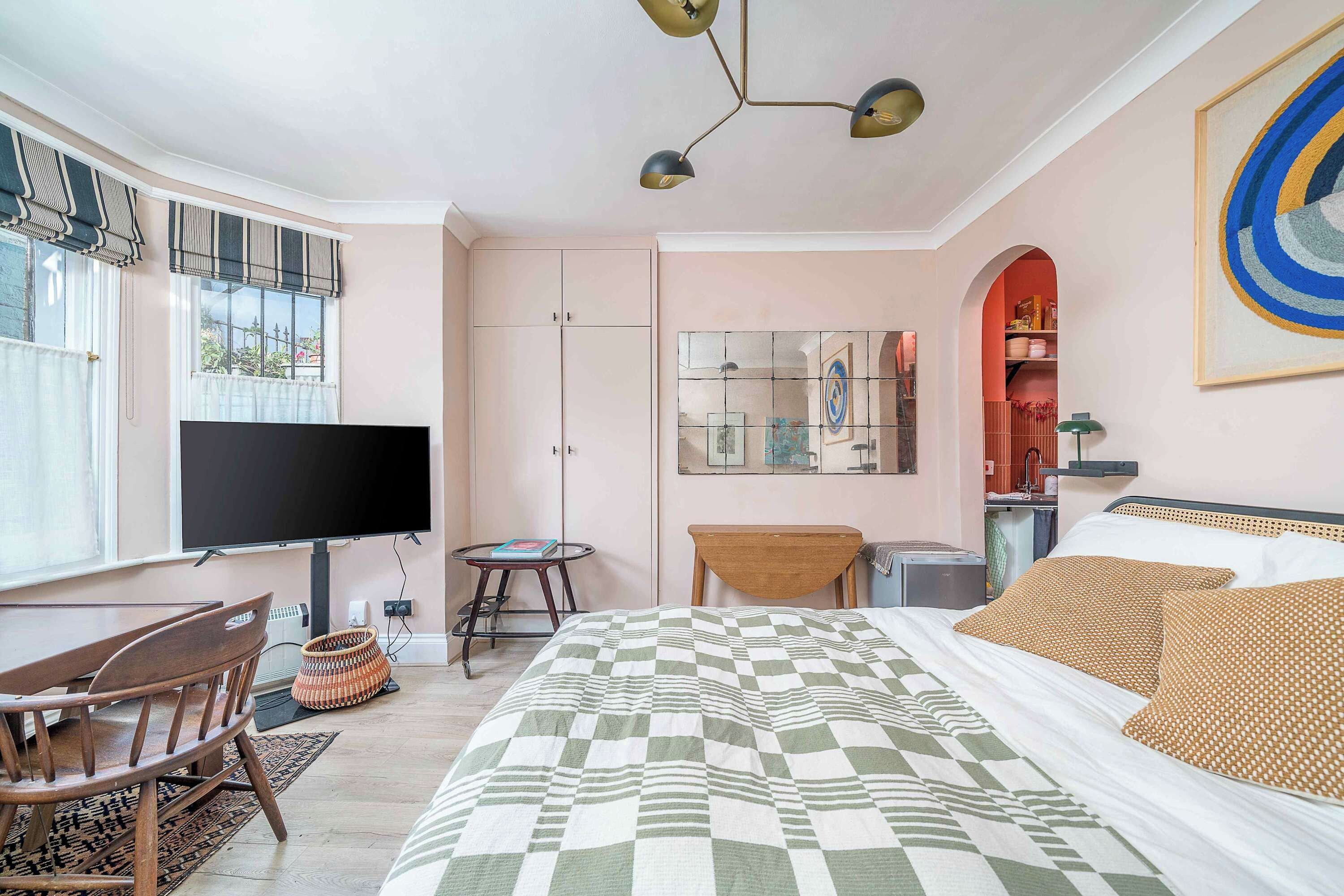 A bedroom with a bed, a TV, a desk, and a chair.