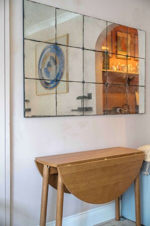 A room with a wooden table and a tiled wall art piece.