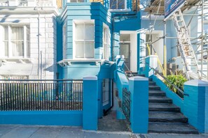 A blue-painted building with a staircase leading to a door.