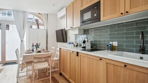 A modern kitchen with wooden cabinets, a built-in microwave, and a tiled backsplash. - Central Bordeaux Gem AC Jacuzzi (Bordeaux)
