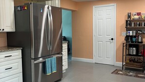 A kitchen with white cabinets, a stainless steel refrigerator, and a white door. - Chill  Cottage in charming Punta Gorda (Punta Gorda)
