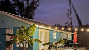 A blue building with a porch, a table with chairs, and a red umbrella. - Chill  Cottage in charming Punta Gorda (Punta Gorda)
