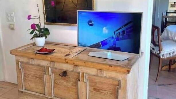 A wooden cabinet with a television and a painting on the wall. - Great apartment in Ilanz (Ilanz Glion)