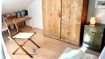 Ein gemütliches Schlafzimmer im Dachgeschoss mit einem Holzschrank, einem weißen Stuhl und einem kleinen Tisch.