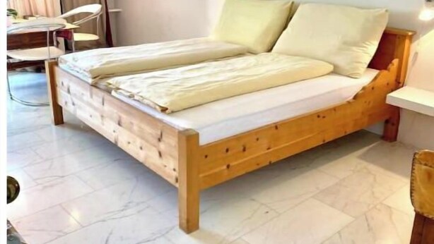 Une chambre à coucher avec un lit en bois, un bureau et une chaise.