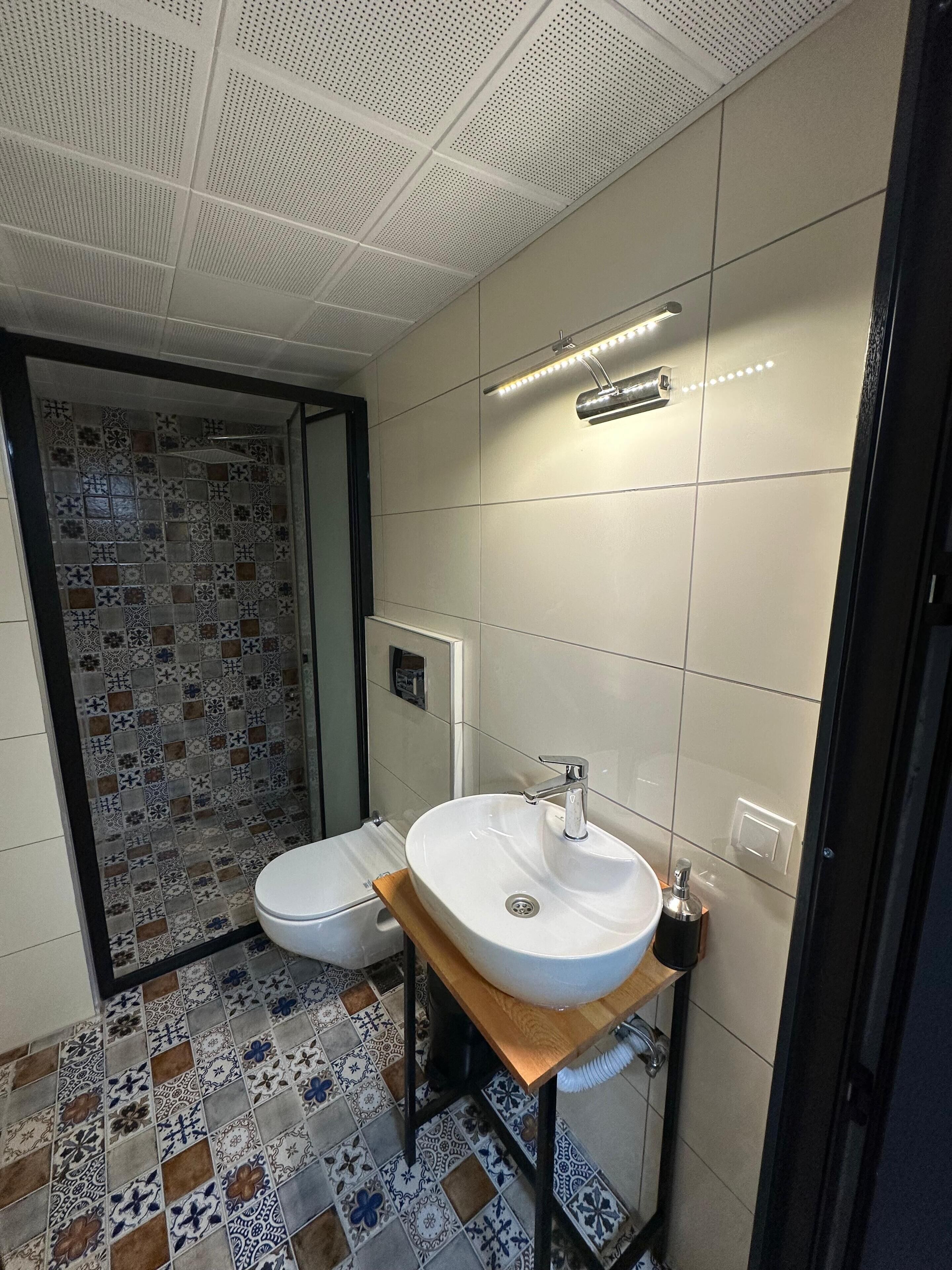 A bathroom with a toilet, sink, and shower area.