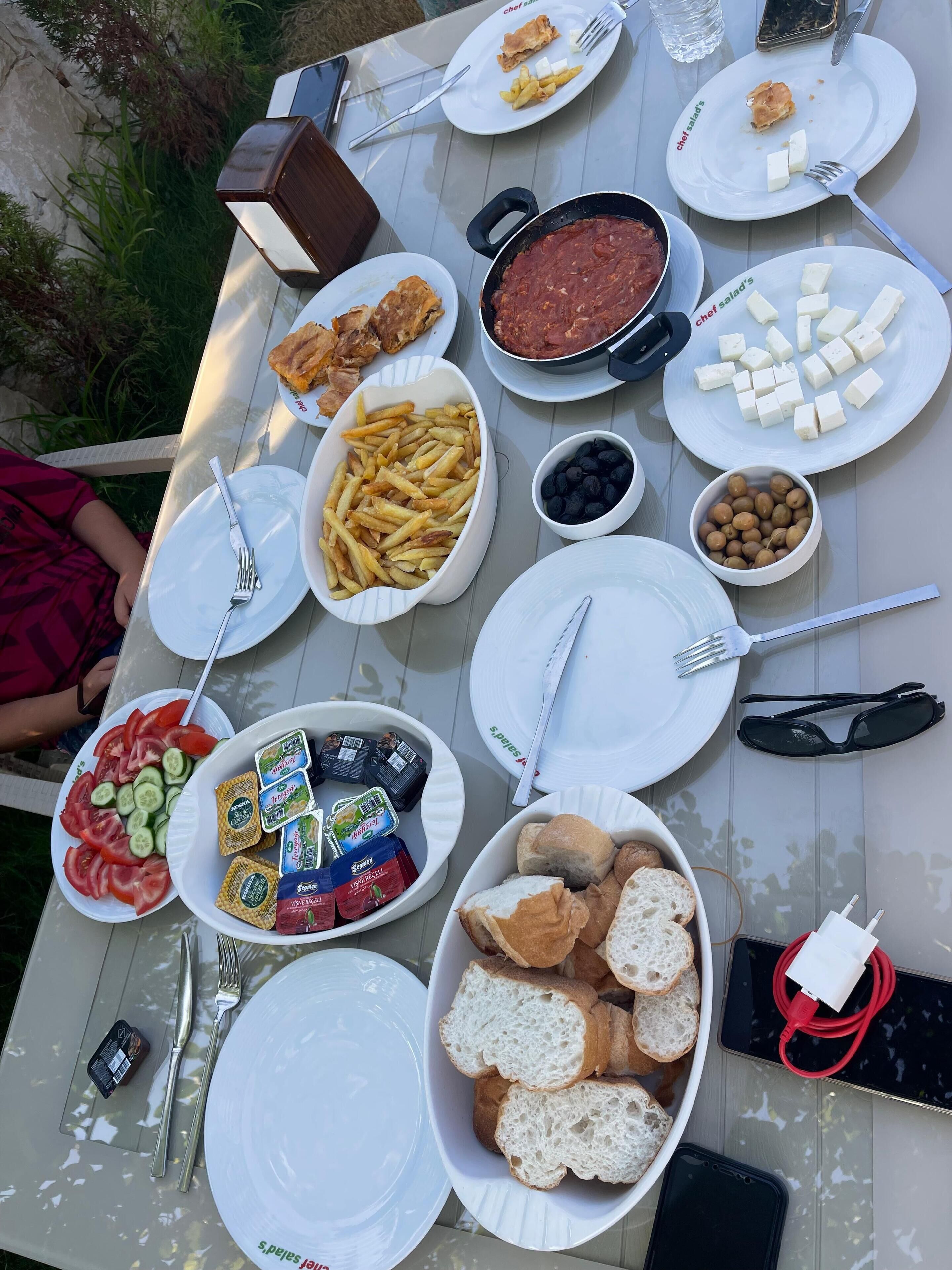 Ein Tisch gedeckt mit verschiedenen Speisen, darunter Brot, Käse und eine Schüssel mit Nüssen.