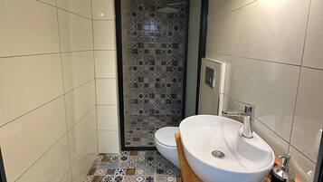 A bathroom with a white sink, a toilet, and a shower area.
