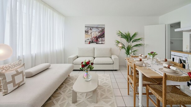Ein modernes Wohnzimmer mit Sofa, Couchtisch, Esstisch für vier Personen und einem Gemälde an der Wand.