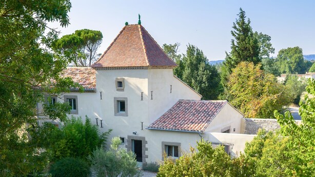 Una villa con techo de tejas, piscina y jardín.