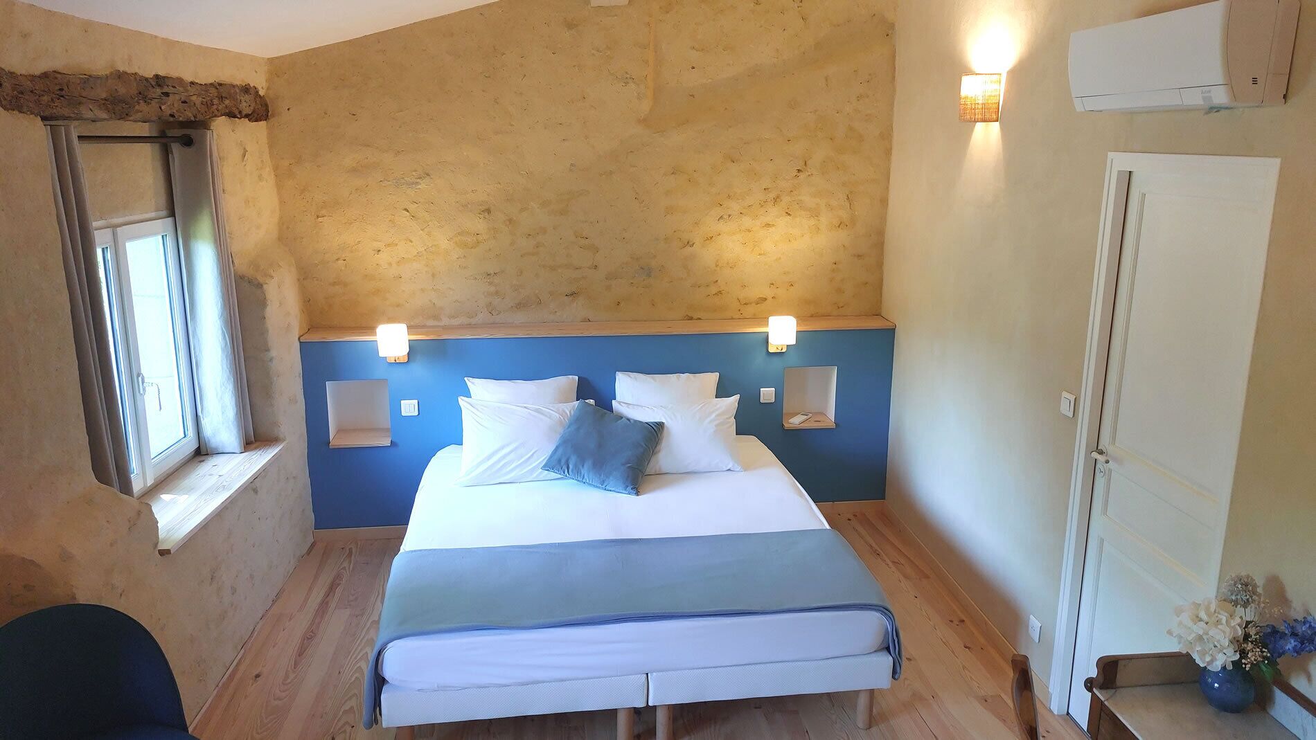 A bedroom with a bed, bedside lamps, a window, and a door.