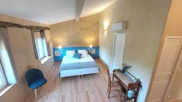 A bedroom with a bed, a chair, a desk, and a window.