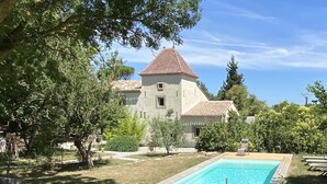 Una casa grande con piscina, rodeada de árboles y un césped cuidado.