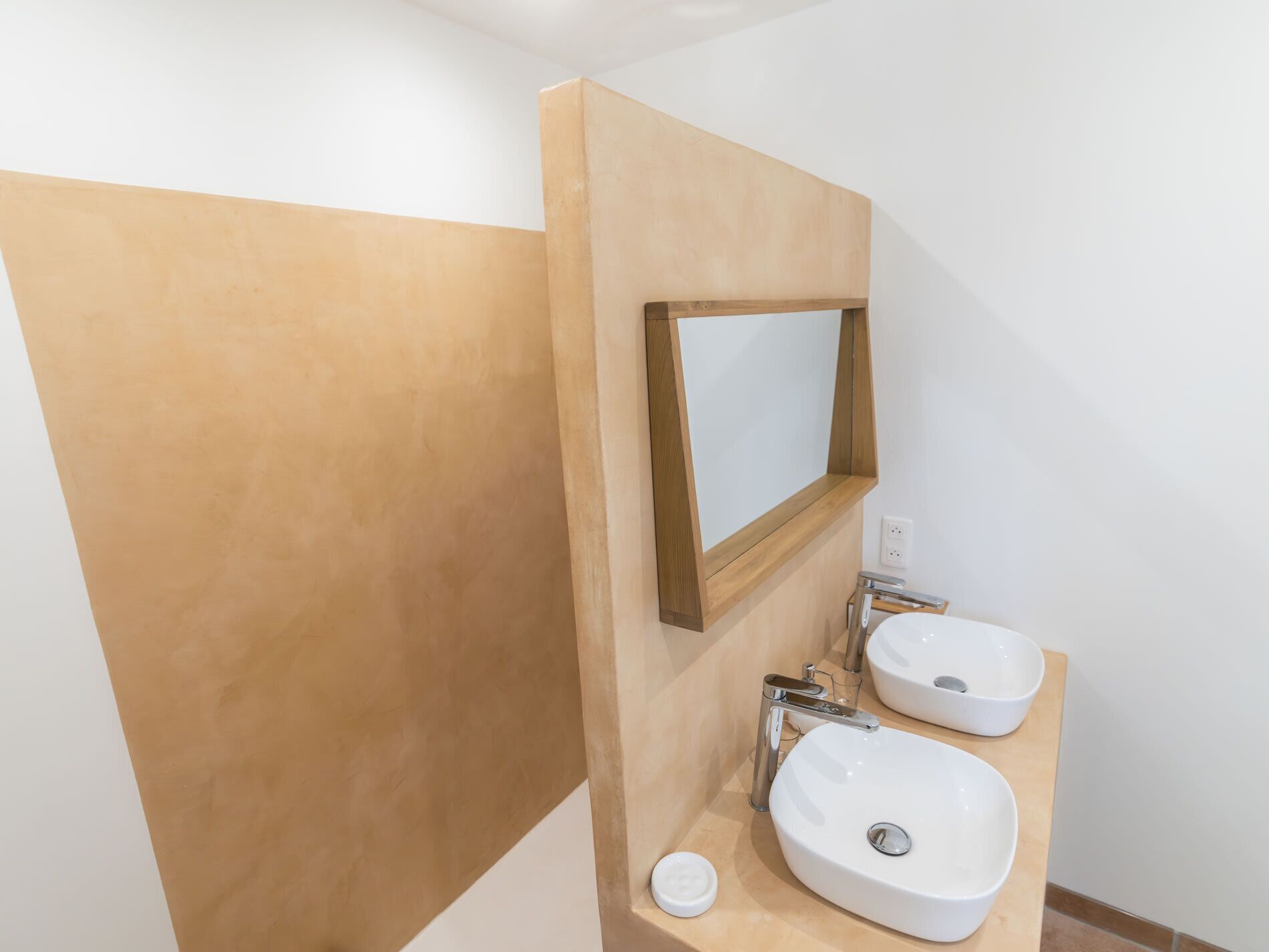 Une salle de bain avec deux lavabos, un miroir et un distributeur de serviettes.