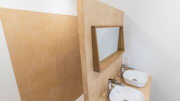 Une salle de bain avec deux lavabos, un miroir et un distributeur de serviettes.