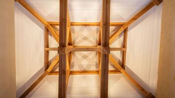 Une pièce dotée d’une structure de plafond en bois et de murs recouverts de panneaux blancs.