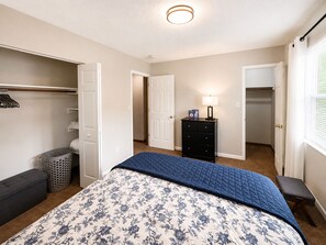 Une chambre à coucher avec un lit, une commode, un placard et une fenêtre.