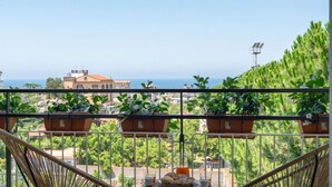 A balcony with potted plants, a wicker chair, and a table with a basket and a cup. - Sorrento Coast Retreat for Families – Terrace & View (Sant'Agnello)