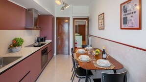 A modern kitchen with a dining area. It includes a stove, sink, and cabinets. There is a dining table set with plates, glasses, and a bottle. - Sorrento Coast Retreat for Families – Terrace & View (Sant'Agnello)