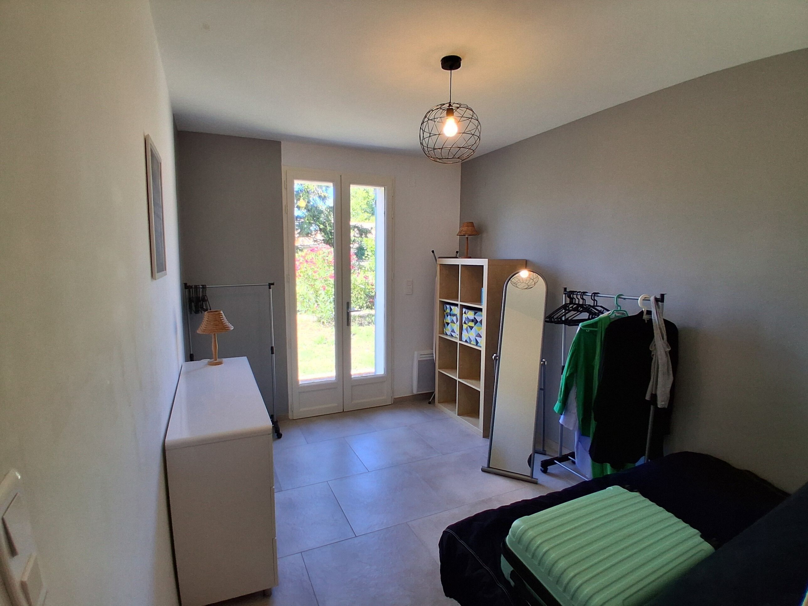 A room with a bed, a wardrobe, a desk, and a door leading to a balcony.