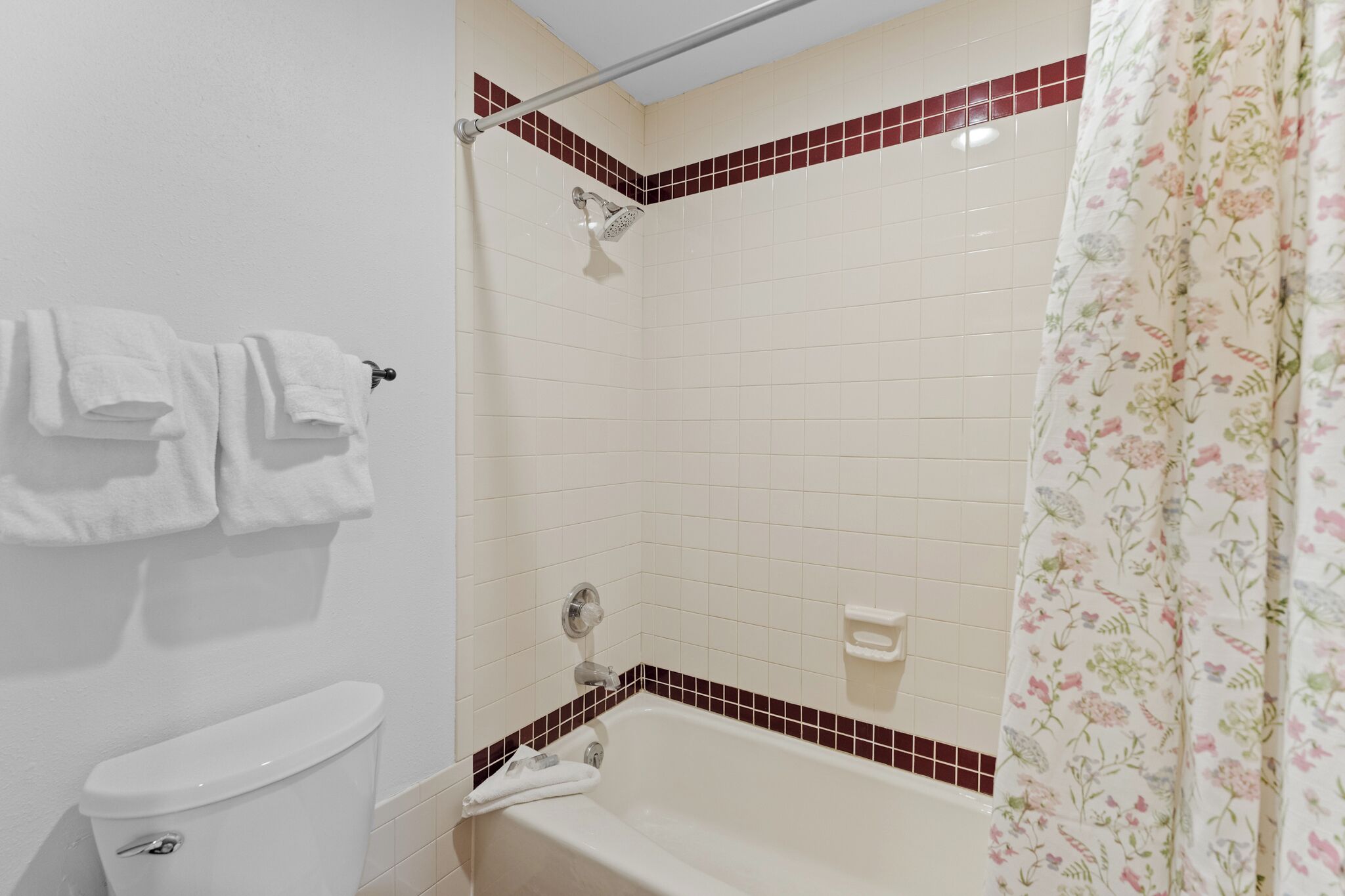 A bathroom with a toilet, a bathtub with a showerhead, and a towel rack.
