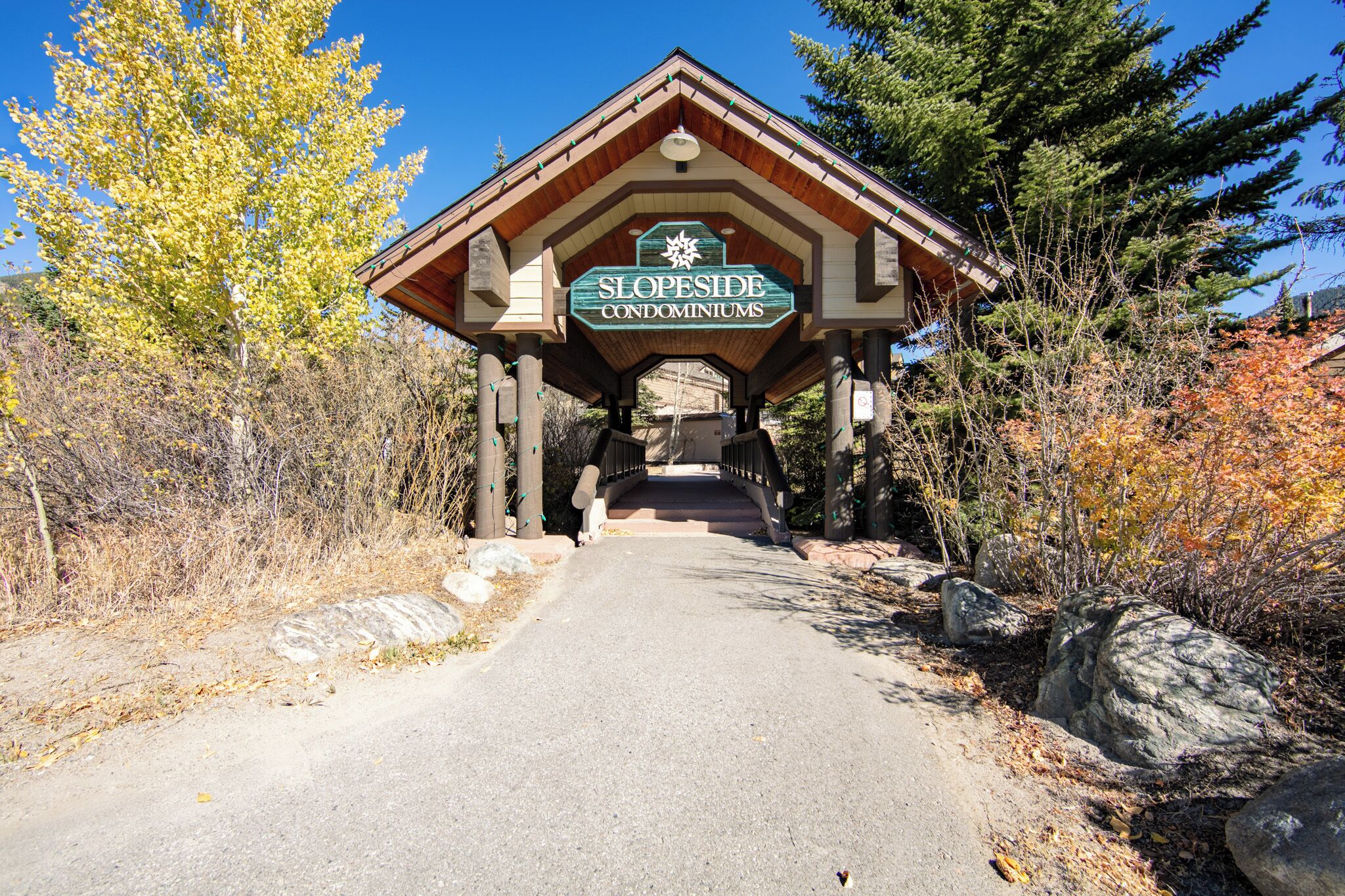 Une structure en bois portant l’inscription « RÉSIDENCES DE PLEIN AIR », avec un chemin bien dégagé menant à celle-ci.