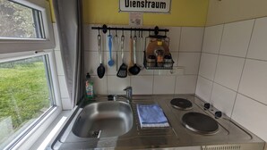 A kitchen with a sink, stove, and utensils hanging on the wall. - Spend the night in a railroad carriage - nostalgia & comfort in Thuringia (Kirchheilingen)