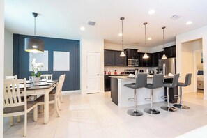 A modern kitchen with dark cabinets, stainless steel appliances, and a central island with bar stools.