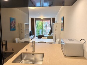 Een moderne keuken met een spoelbak, een ingebouwde oven en een eethoek met een tafel en stoelen.