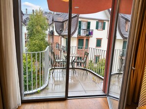 Un balcon avec une porte-fenêtre, une table et deux chaises.