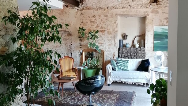 A rustic room with exposed wooden beams, a green chair, a white sofa, and a dining table with a bowl. - Charming, quiet house with patio and pool. Surrounding countryside (Sabran)