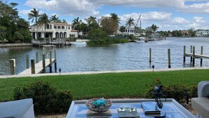 A waterfront view with a dock, a boat, and a building with arched windows.