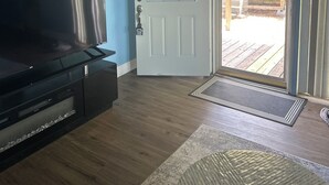 Una sala de estar con televisor de pantalla plana, una puerta blanca con ventana y techo de madera.