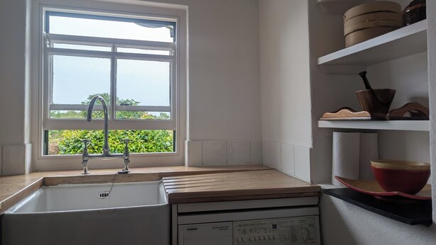 A kitchen with a window, a sink, and a Siemens washing machine. - Charming 2-bedroom Cottage near Skibbereen with stove and views. (Skibbereen)