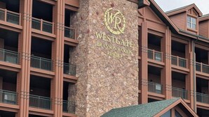 Un edificio de varios pisos con fachada de piedra y un letrero que dice 'Westgate Branson Woods Resort'.